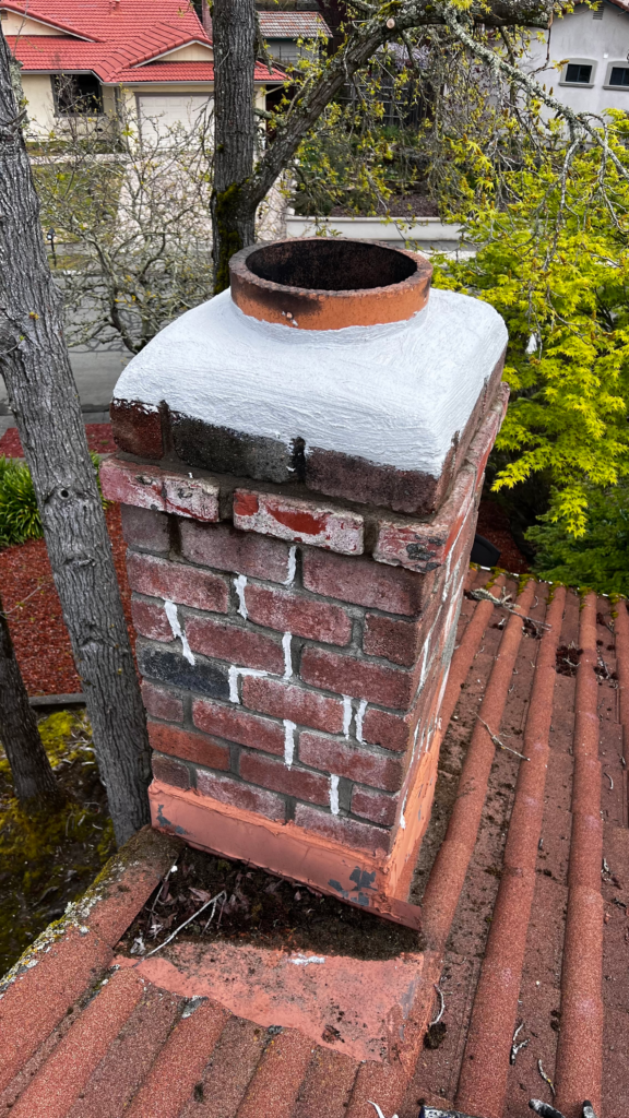 chimney inspection of red brick chimney on rooftop without a chimney cap.