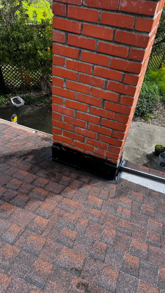 Red brick chimney with black chimney cap on coastal home roof in Half Moon Bay CA