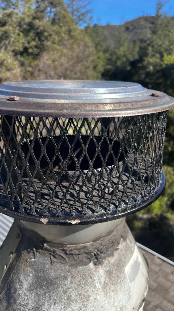 Gray chimney cap with protective mesh screen installed on residential chimney in Concord CA