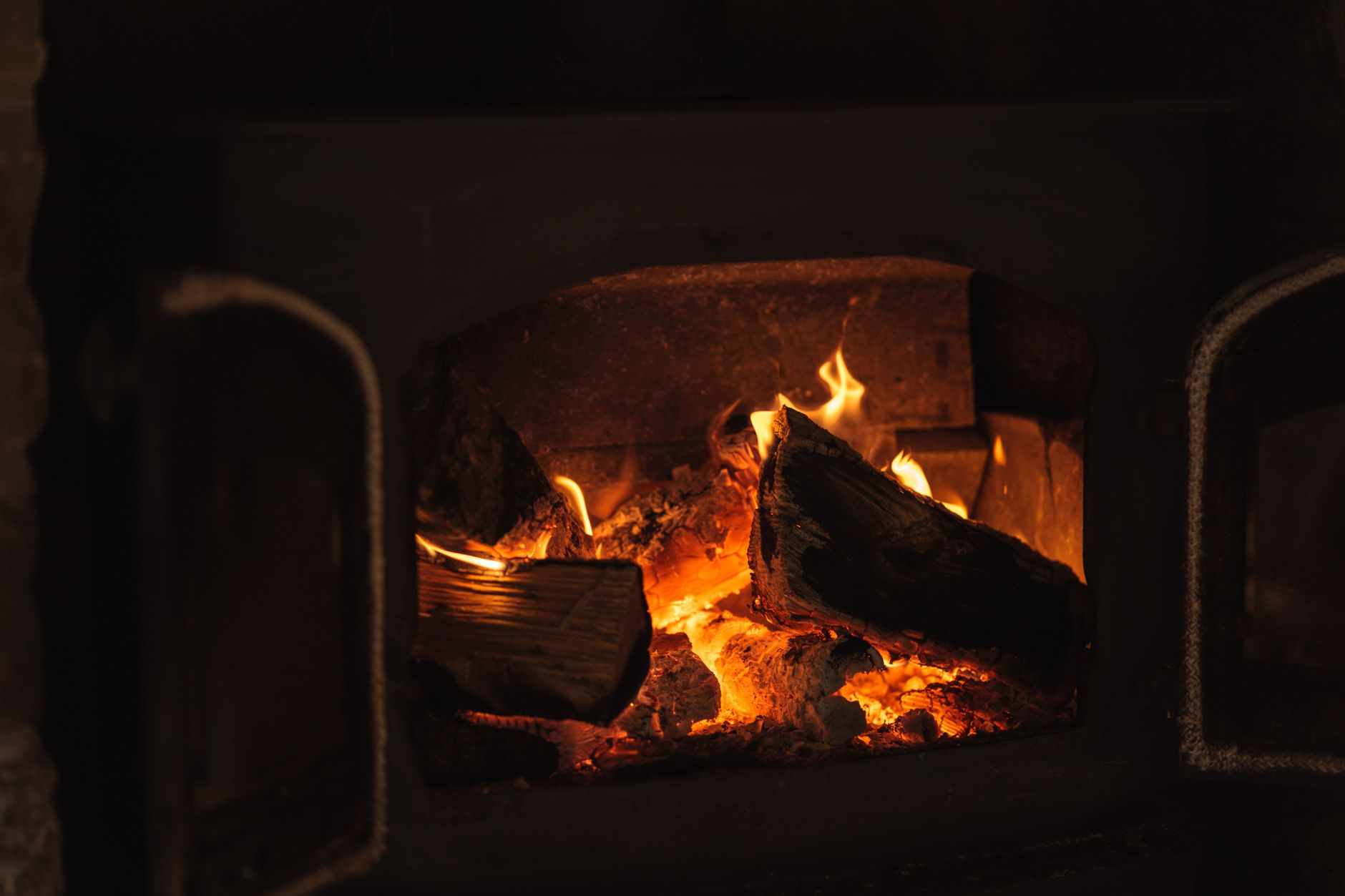 Cut wood burning in fireplace with bright orange flames, representing wood-burning fireplace service for Bay Area homes
