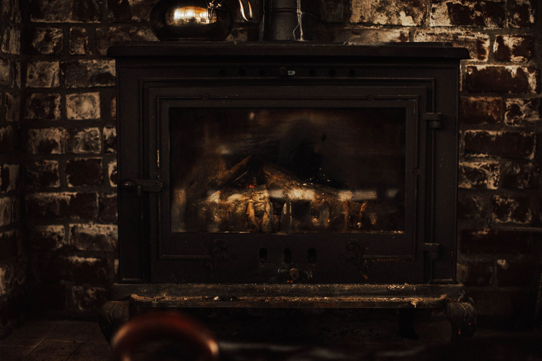 Vintage brick fireplace glowing warmly, the kind kept clean with professional chimney sweeping services in the Bay Area