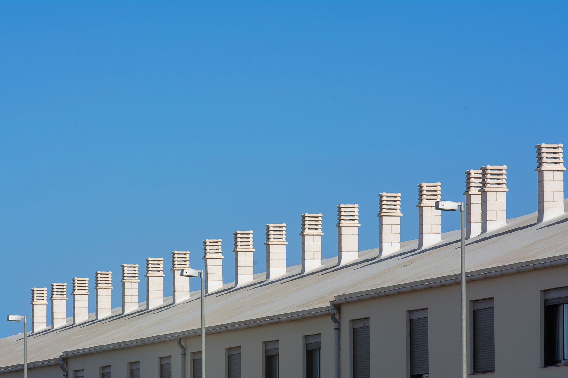 Row of modern rooftop chimneys with caps under blue sky, inspiration for chimney cap installation in the Bay Area